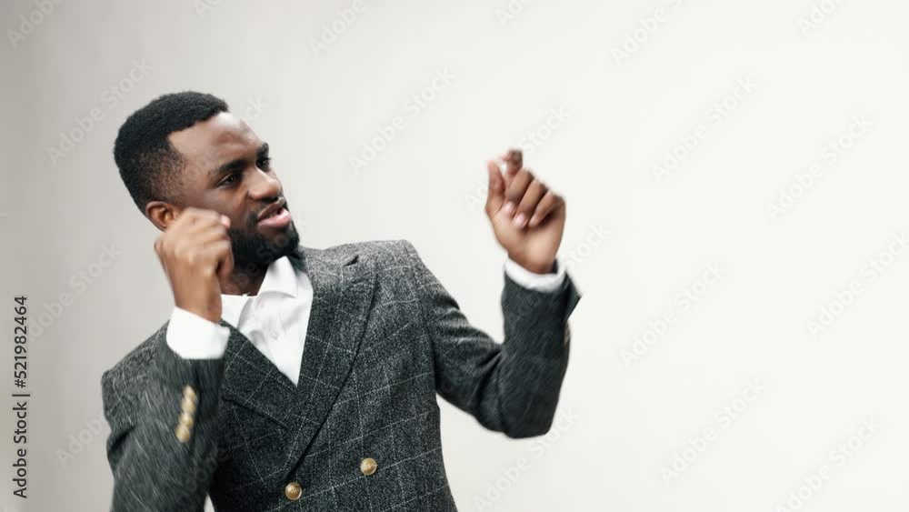 An African-American businessman man dancing to music in his head in his office against a white background in a business suit and happy Friday, days off and time off from work