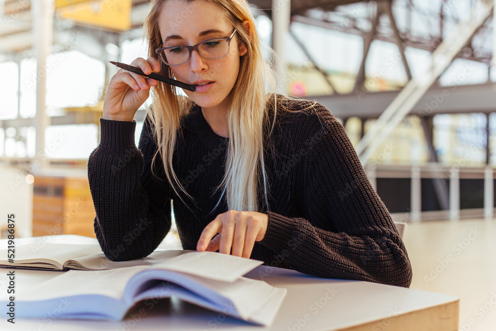 Focused woman reading books on desk in library Focused woman reading books on desk in library