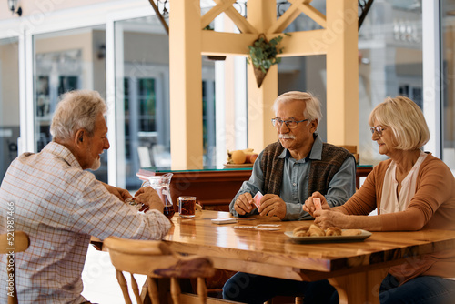 Group of senior people playing cards on patio at nursing home. photo