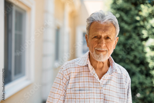 Portrait of senior man outdoors at nursing home looking at camera.
