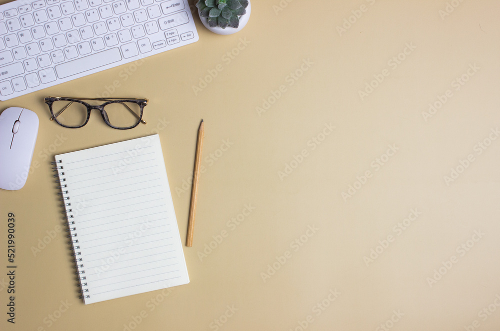 Computer with notebook, green leaves with glasses and pencil over the brown background. Computer with notebook, green leaves with glasses and pencil over the brown background.