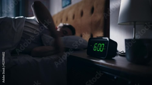 Handsome Man Wakes Up and Turns off Alarm Clock. Proceeds to Have a Productive Day of Work. Stylish Apartment. Focus on the Clock Showing Six O'Clock. Bedroom Apartment