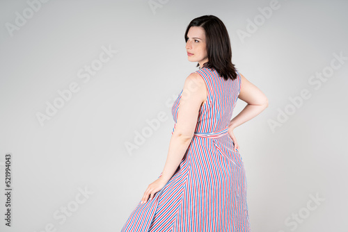 Plus size model in casual clothes, fat woman on gray background, overweight female body