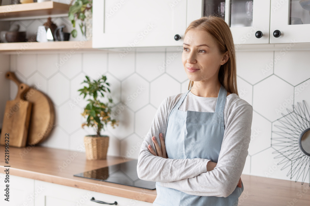 Smiling woman in apron looking away in kitchen