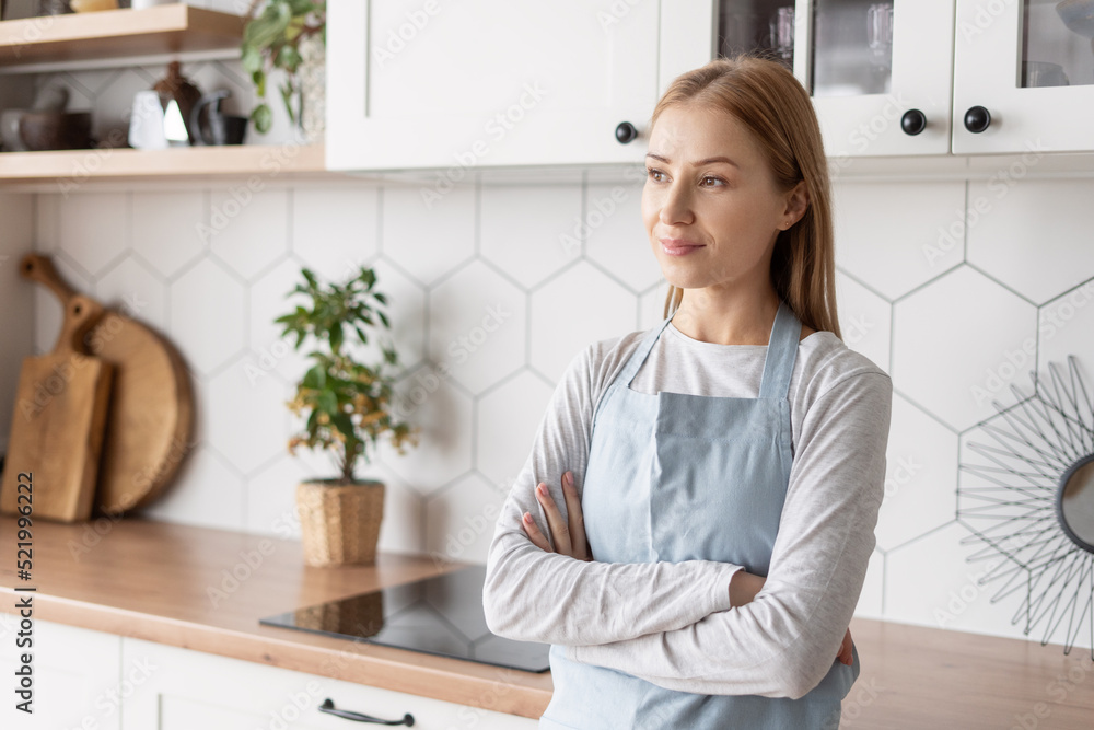 Smiling woman in apron looking away in kitchen Smiling woman in apron looking away in kitchen