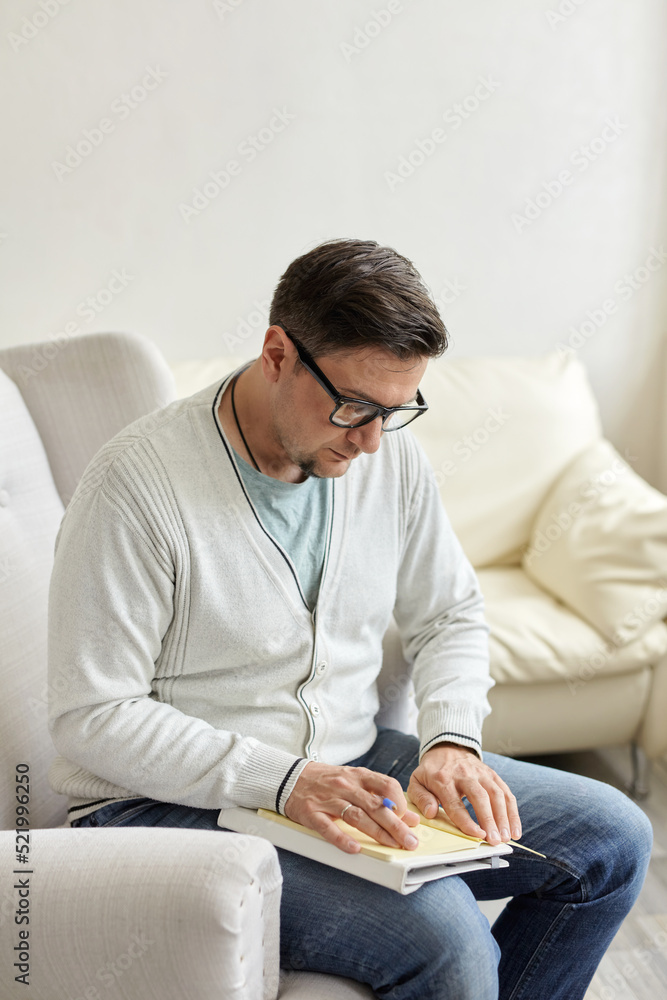 Friendly psychologist with clipboard, leaning at wall in office, empty space Friendly psychologist with clipboard, leaning at wall in office, empty space