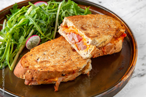 Big toast fried in an egg with meat, vegetables and herbs in a  plate on a marble background. Restaurant banquet menu.