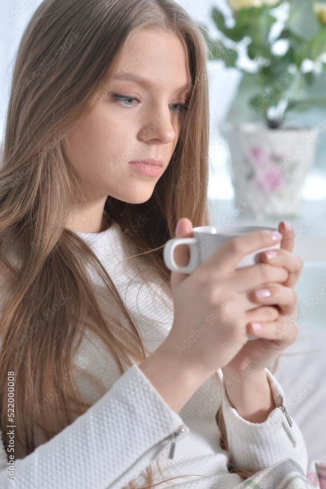 Young attractive woman with cup of tea in cozy armchair Young attractive woman with cup of tea in cozy armchair