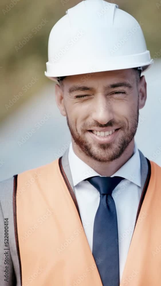 vertical video of happy businessman in hardhat and safety vest looking at camera vertical video of happy businessman in hardhat and safety vest looking at camera