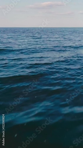 vertical video of blue tranquil sea with waves and skyline photo