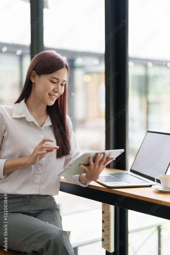 Portrait of an Asian female employee using a tablet computer at work. Portrait of an Asian female employee using a tablet computer at work.