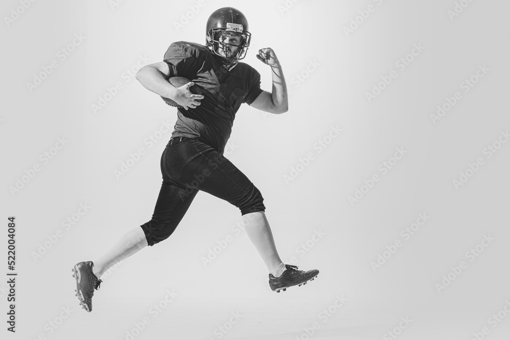 Dynamic portrait of american football player in action and motion isolated on white background. Concept of sport, achievements, retro style. Monochrome