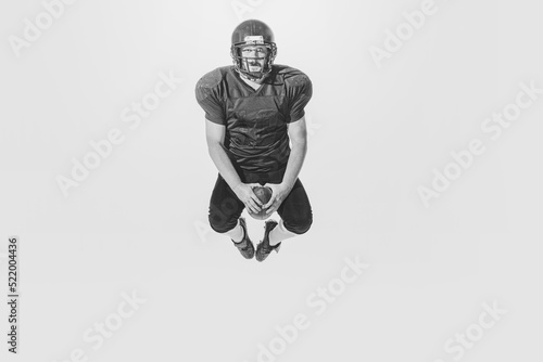 One american football player wearing retro stlye sports uniform in action and motion isolated on white background. Monochrome