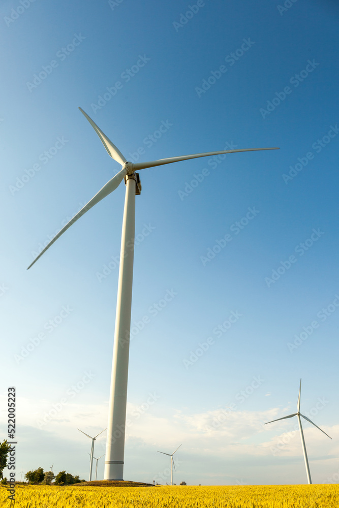 Landsape with Windmills on wheat field and blue sky