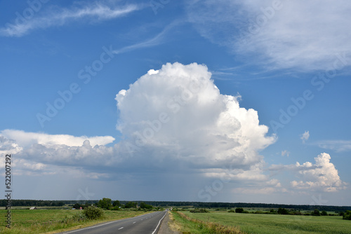 Thunderclouds on a summer day and a road in the countryside. A thunderstorm on a bright day.