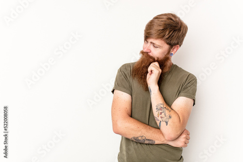 Young caucasian red-haired man isolated on white background looking sideways with doubtful and skeptical expression.