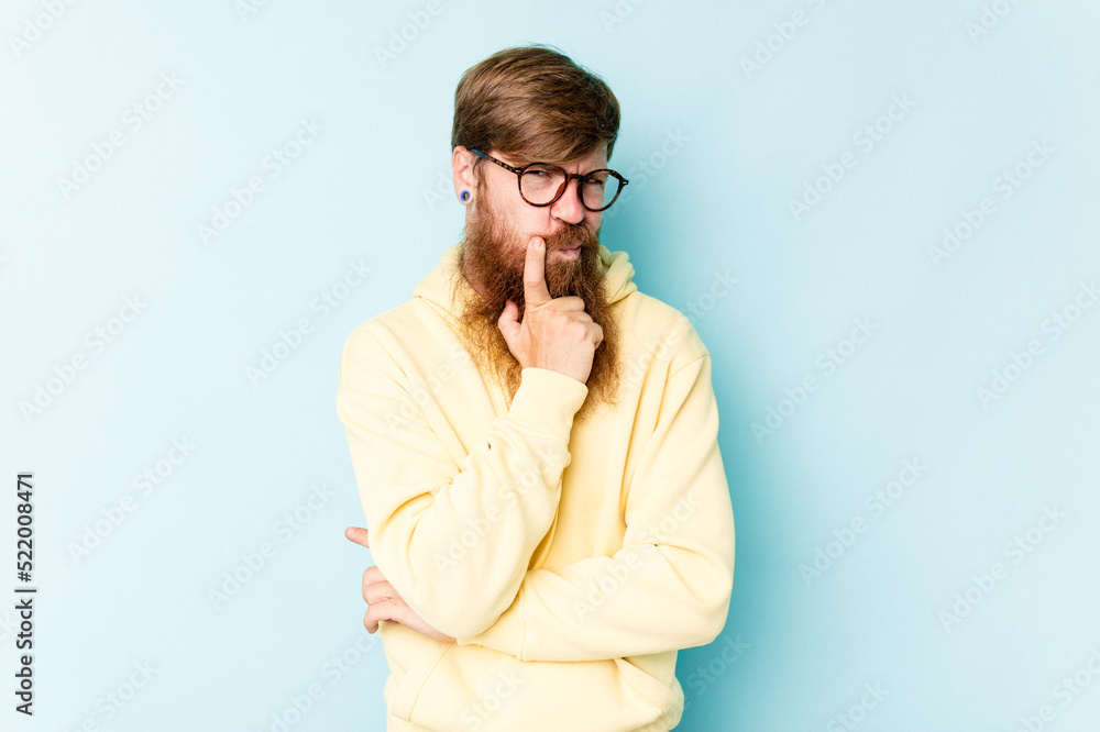 Young caucasian red-haired man isolated on blue background contemplating, planning a strategy, thinking about the way of a business. Young caucasian red-haired man isolated on blue background contemplating, planning a strategy, thinking about the way of a business.