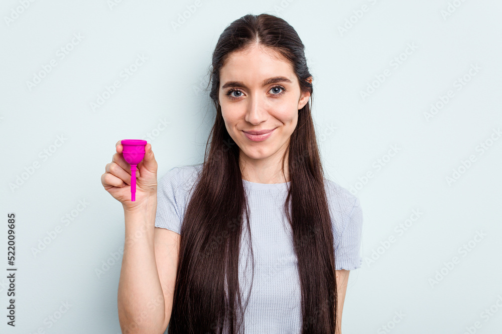 Young caucasian woman holding a sanitary napkin isolated on blue background happy, smiling and cheerful. Young caucasian woman holding a sanitary napkin isolated on blue background happy, smiling and cheerful.