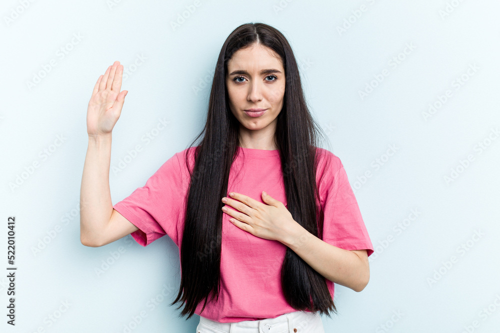 Young caucasian woman isolated on blue background taking an oath, putting hand on chest. Young caucasian woman isolated on blue background taking an oath, putting hand on chest.