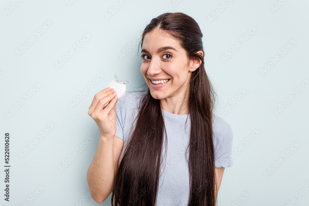 Young caucasian woman getting a dental whitening isolated on blue background Young caucasian woman getting a dental whitening isolated on blue background