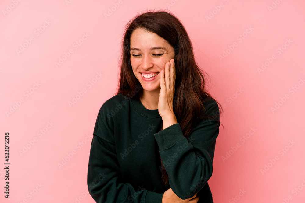 Young caucasian woman isolated on pink background laughs happily and has fun keeping hands on stomach. Young caucasian woman isolated on pink background laughs happily and has fun keeping hands on stomach.