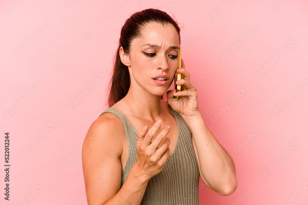 Young caucasian woman holding mobile phone isolated on pink background Young caucasian woman holding mobile phone isolated on pink background
