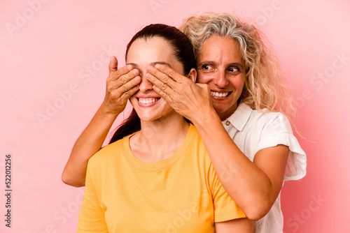 Caucasian mom and daughter isolated on pink background © Asier