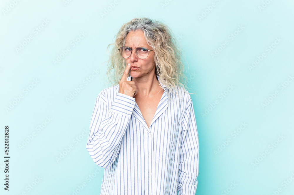 Middle age caucasian woman isolated on blue background keeping a secret or asking for silence. Middle age caucasian woman isolated on blue background keeping a secret or asking for silence.