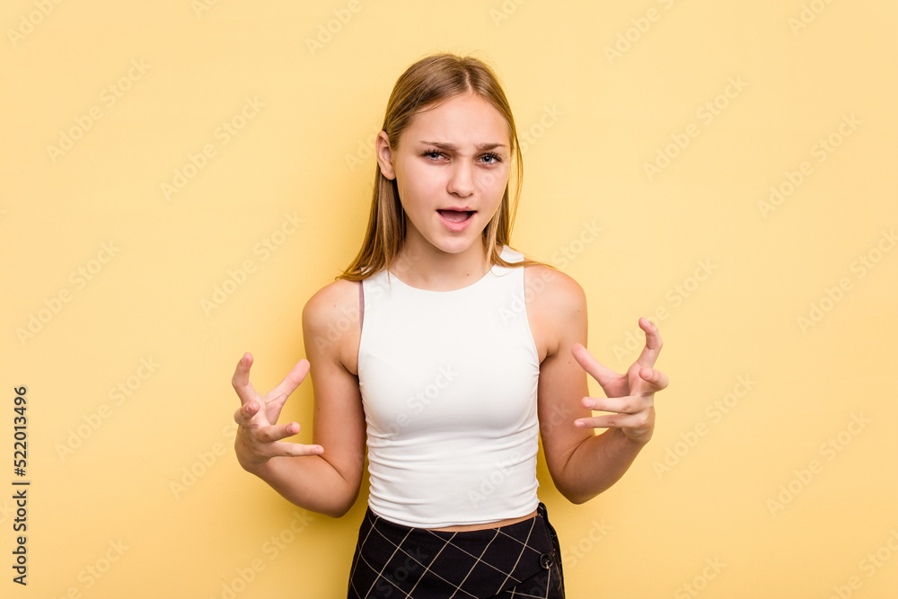 Young caucasian girl isolated on yellow background screaming with rage. Young caucasian girl isolated on yellow background screaming with rage.