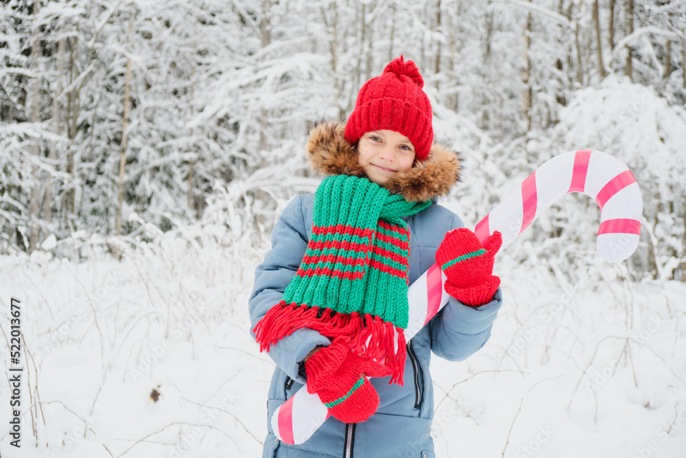 teenage girl in warm snake clothes in christmas flowers outdoor, child playing with big inflatable candy cane teenage girl in warm snake clothes in christmas flowers outdoor, child playing with big inflatable candy cane
