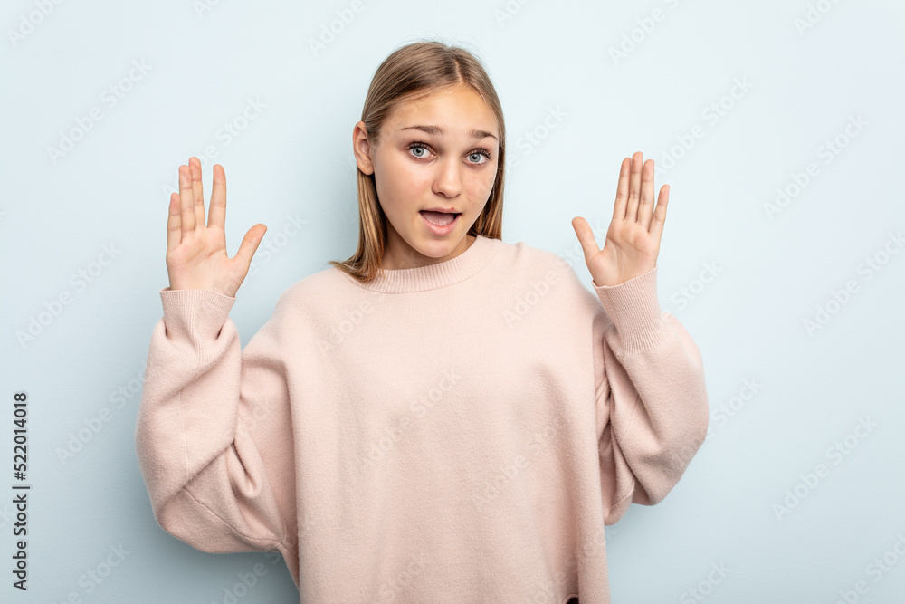 Young caucasian girl isolated on blue background receiving a pleasant surprise, excited and raising hands. Young caucasian girl isolated on blue background receiving a pleasant surprise, excited and raising hands.