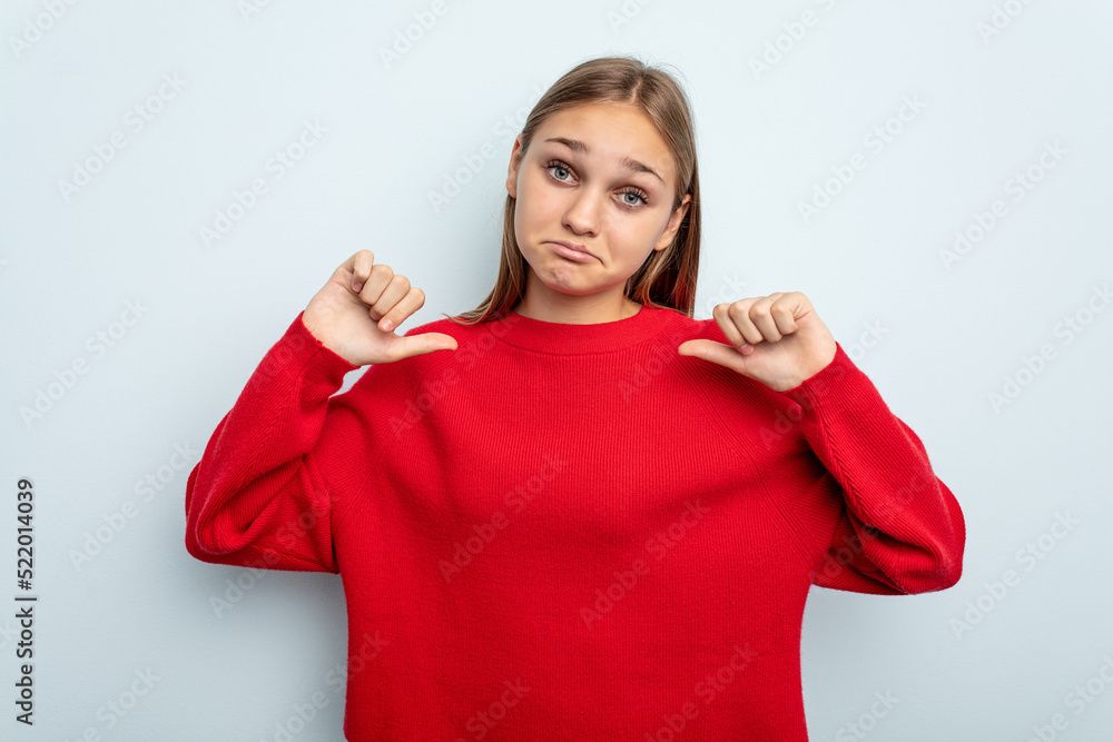 Young caucasian girl isolated on blue background feels proud and self confident, example to follow. Young caucasian girl isolated on blue background feels proud and self confident, example to follow.