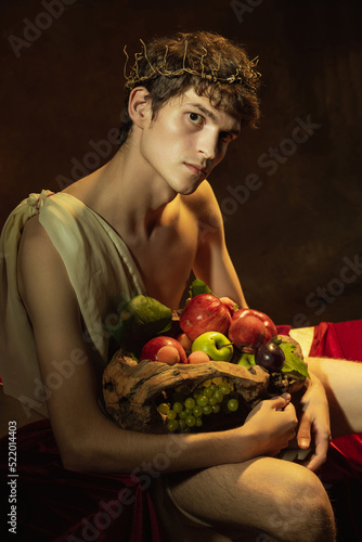 Creative remake of painting boy with a basket of fruit. Young handsome man over dark vintage background. Italian baroque style, art, creativity, vintage photo