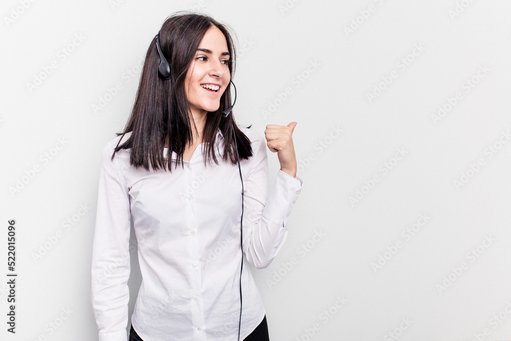 Telemarketer caucasian woman working with a headset isolated on white background points with thumb finger away, laughing and carefree. Telemarketer caucasian woman working with a headset isolated on white background points with thumb finger away, laughing and carefree.