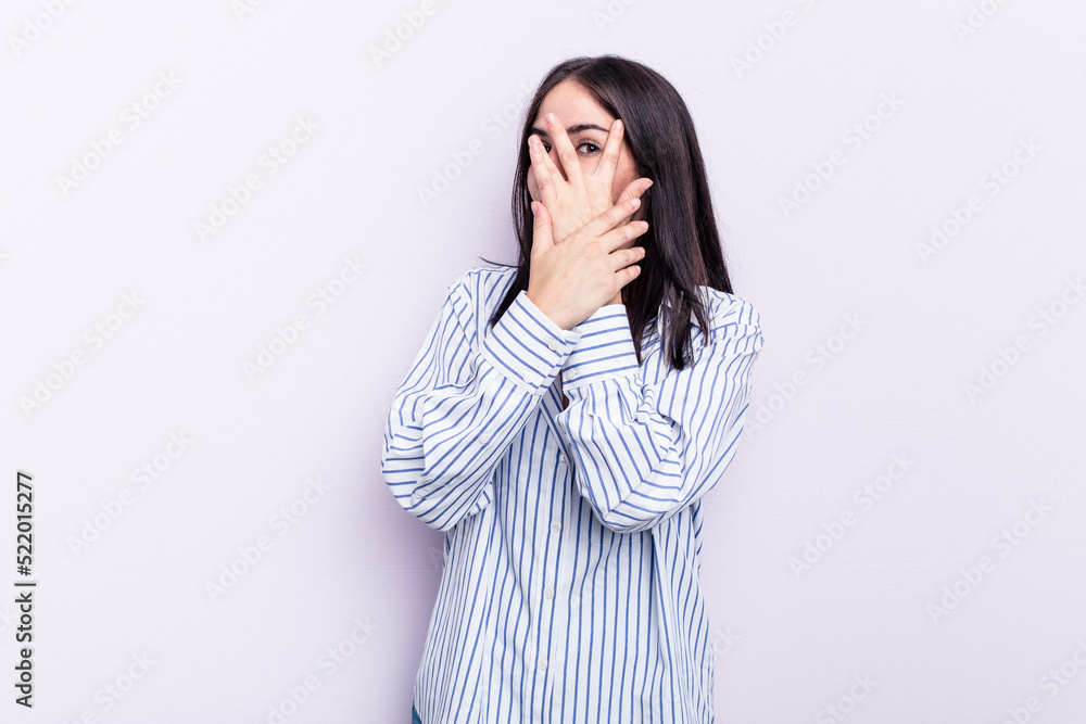 Young caucasian woman isolated on pink background blink through fingers frightened and nervous. Young caucasian woman isolated on pink background blink through fingers frightened and nervous.