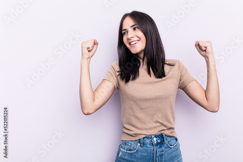 Young caucasian woman isolated on pink background raising fist after a victory, winner concept.