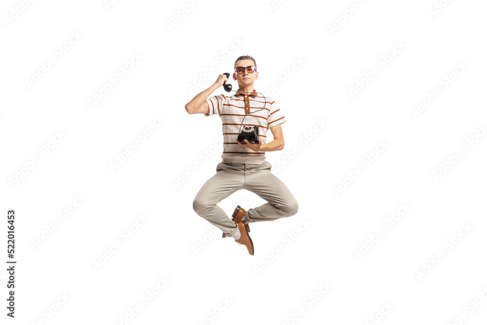Portrait of stylish man in retro outfit talking on vintage phone in a jump isolated over white studio background