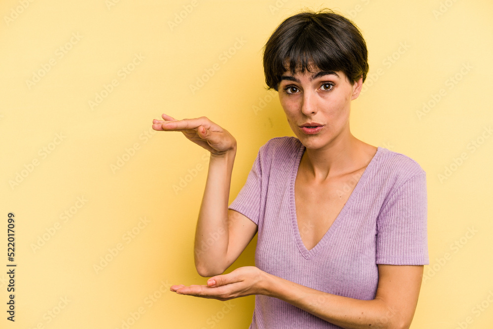 Young caucasian woman with a short hair cut isolated shocked and amazed holding a copy space between hands. Young caucasian woman with a short hair cut isolated shocked and amazed holding a copy space between hands.