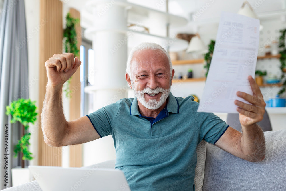Surprised laughing happy old mature retired man looking through paper document, feeling excited analyzing financial information, getting taxes refund or bank loan approval at home. Surprised laughing happy old mature retired man looking through paper document, feeling excited analyzing financial information, getting taxes refund or bank loan approval at home.