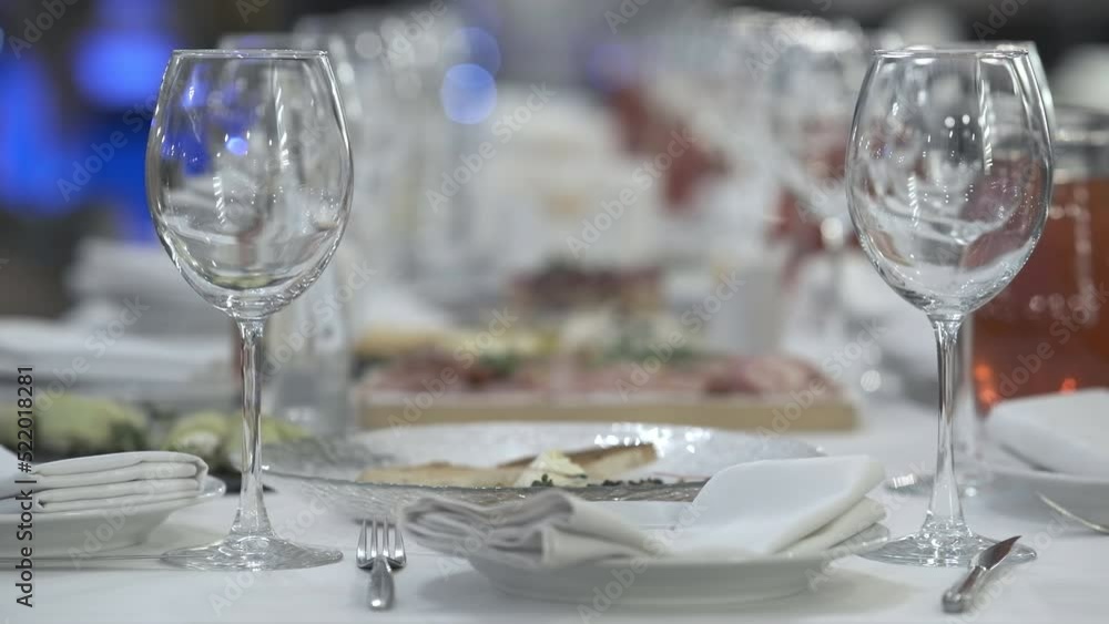 A group of transparent empty clean wine glasses stand on a shelf under artificial light. Clean champagne glasses nearby. A group of transparent empty clean wine glasses stand on a shelf under artificial light. Clean champagne glasses nearby.