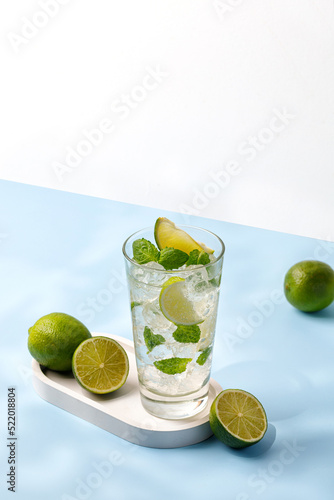 Delicious refreshing summer mojito with ice, lime and mint in a glass with grops. Sunshine. Copy space. Cold lemonade, tonic.