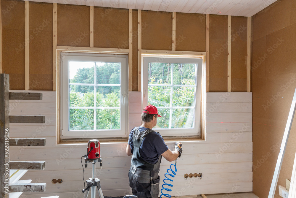 Fototapeta premium Construction worker thermally insulating eco wooden frame house