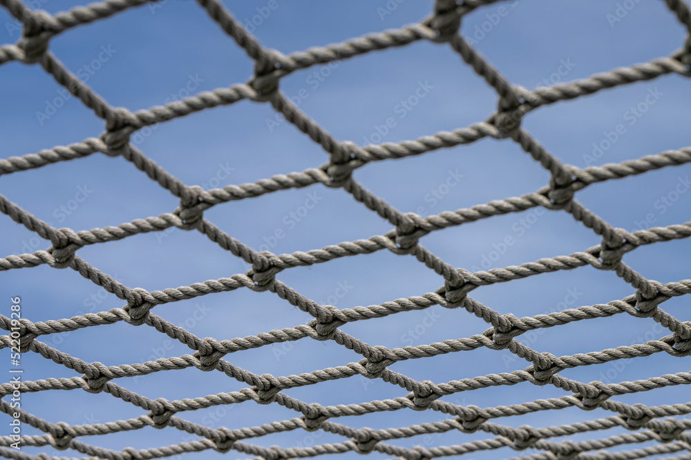 Knotted net against a blue sky.