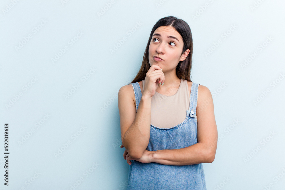 Young caucasian woman isolated on blue background looking sideways with doubtful and skeptical expression. Young caucasian woman isolated on blue background looking sideways with doubtful and skeptical expression.