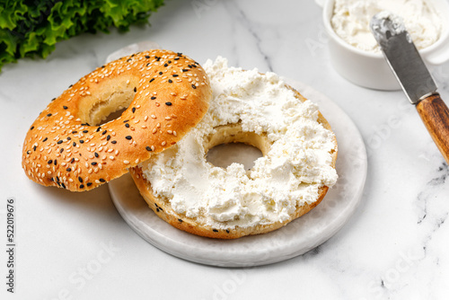 Bild auf Leinwand Bagel sandwich with cream cheese on marble board and white background