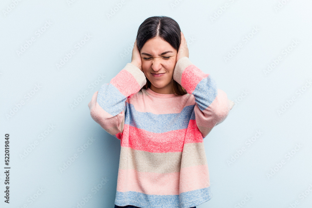 Young caucasian woman isolated on blue background covering ears with hands. Young caucasian woman isolated on blue background covering ears with hands.
