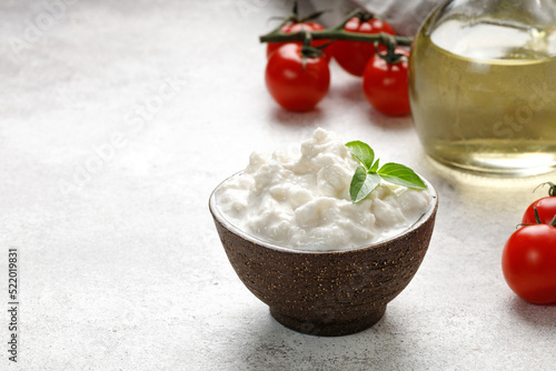 Stracciatella cheese on grey background with oil, basil and tomatoes. Curd cheese product. photo