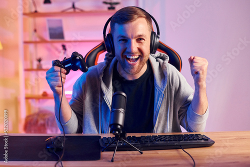 Celebrating victory. Man in headphones and with microphone is live on the stream