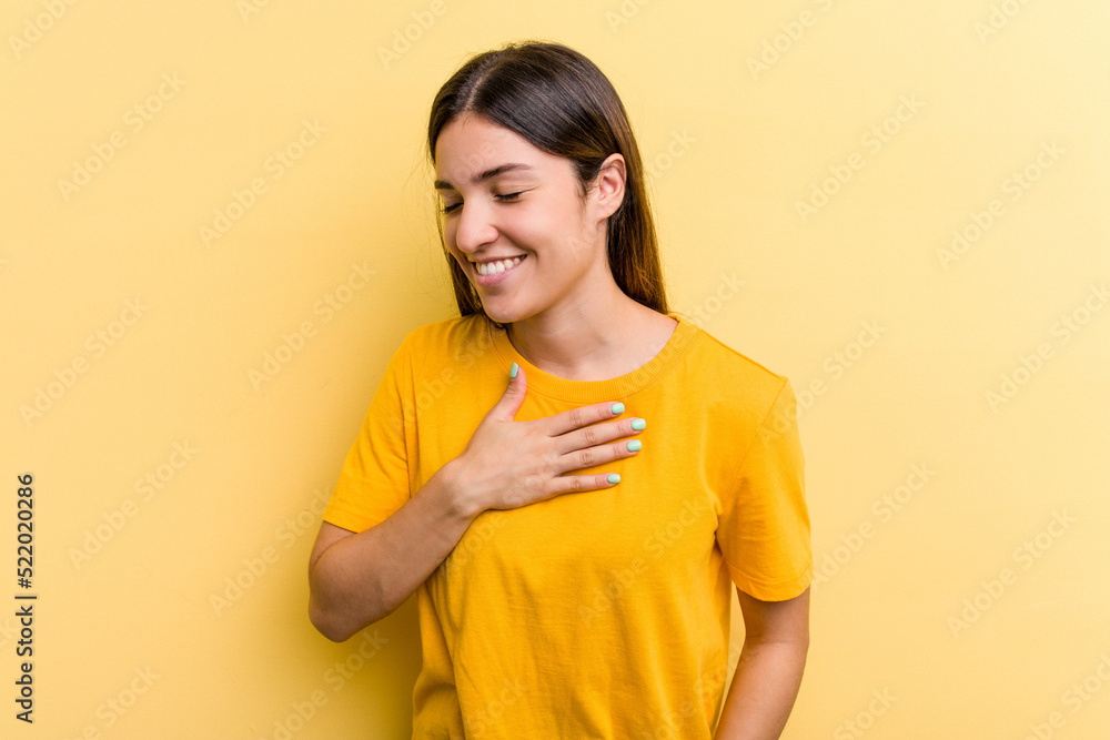 Young caucasian woman isolated on yellow background laughing keeping hands on heart, concept of happiness.