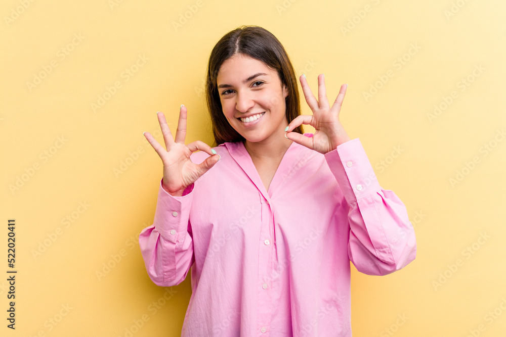 Young caucasian woman isolated on yellow background cheerful and confident showing ok gesture.